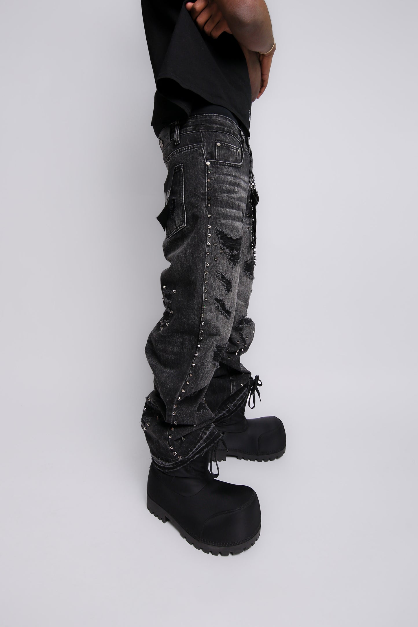 Person wearing black distressed cargo pants and black boots on a light gray background