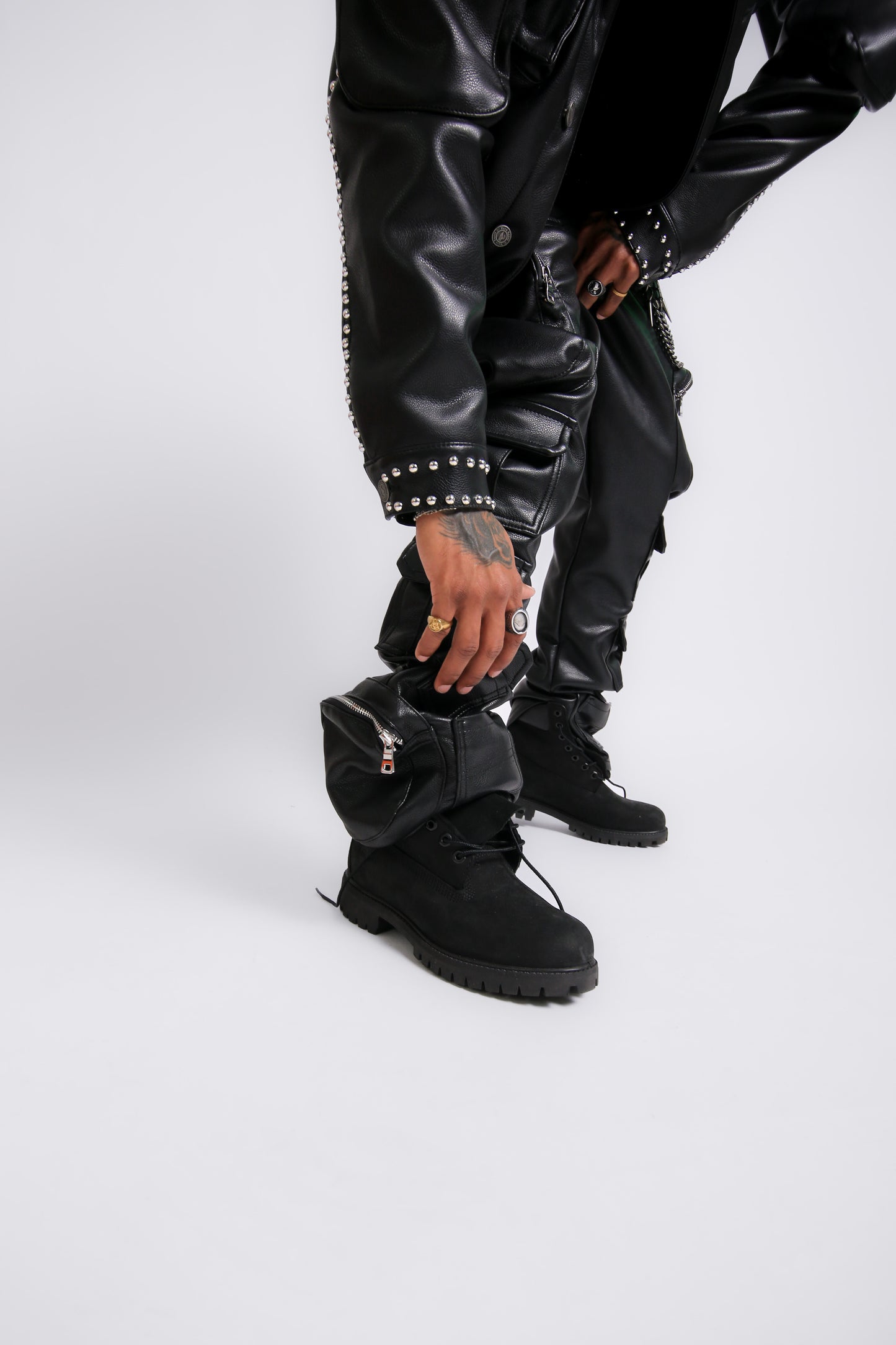 Person wearing black leather jacket, pants, and boots on a white background