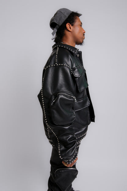 Person wearing a black leather jacket with studs on a gray background