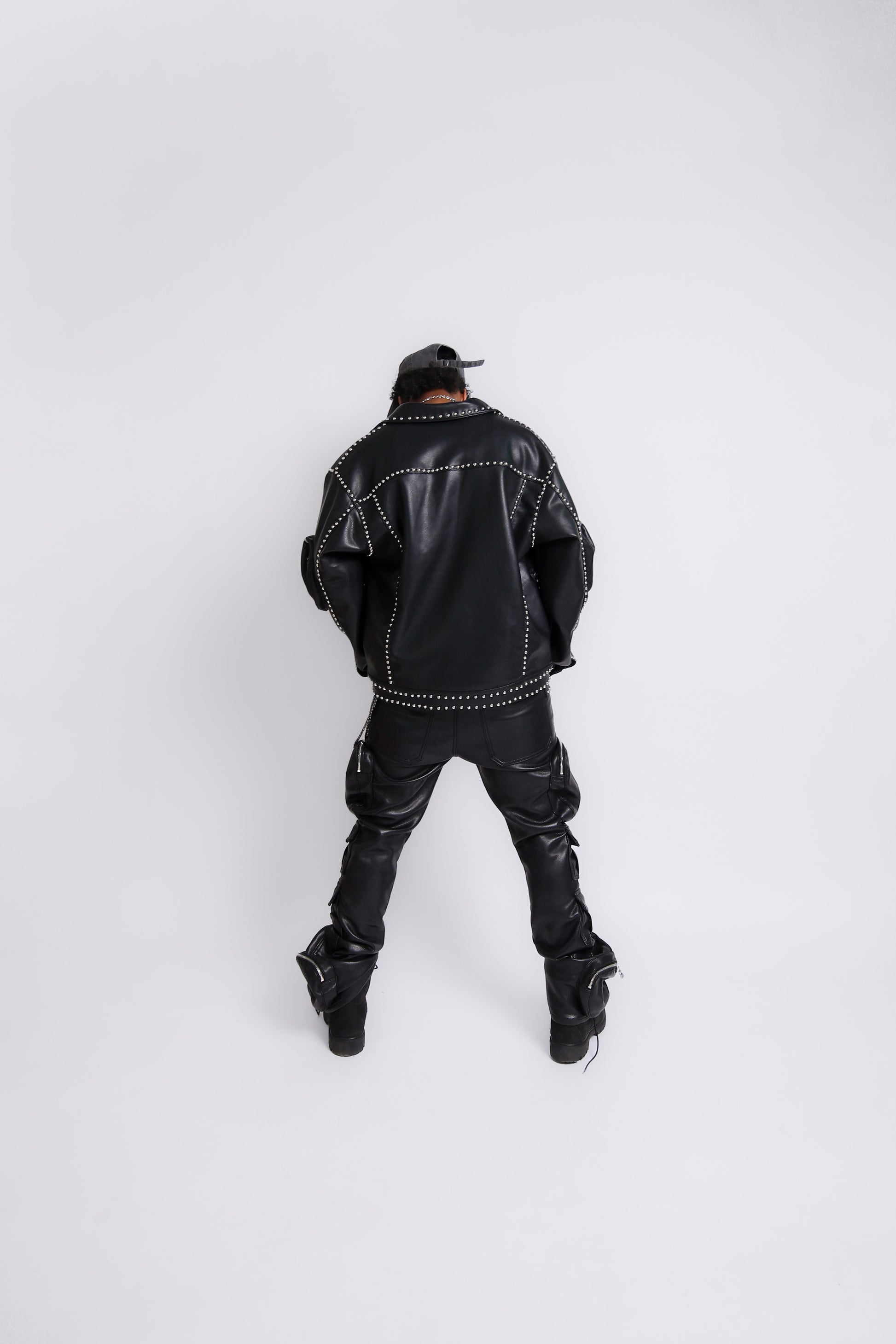 Person wearing a black leather jacket and pants on a white background
