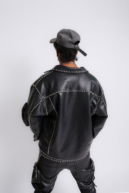 Person wearing a black leather jacket with studs and pants on a white background
