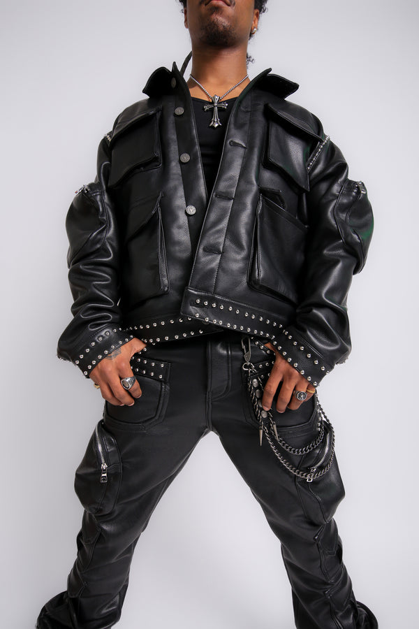 Person wearing a black leather jacket with studded details on a white background