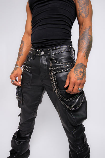 Person wearing black leather pants with studs and chains on a white background