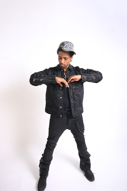 Person wearing a black denim jacket and pants with a white background