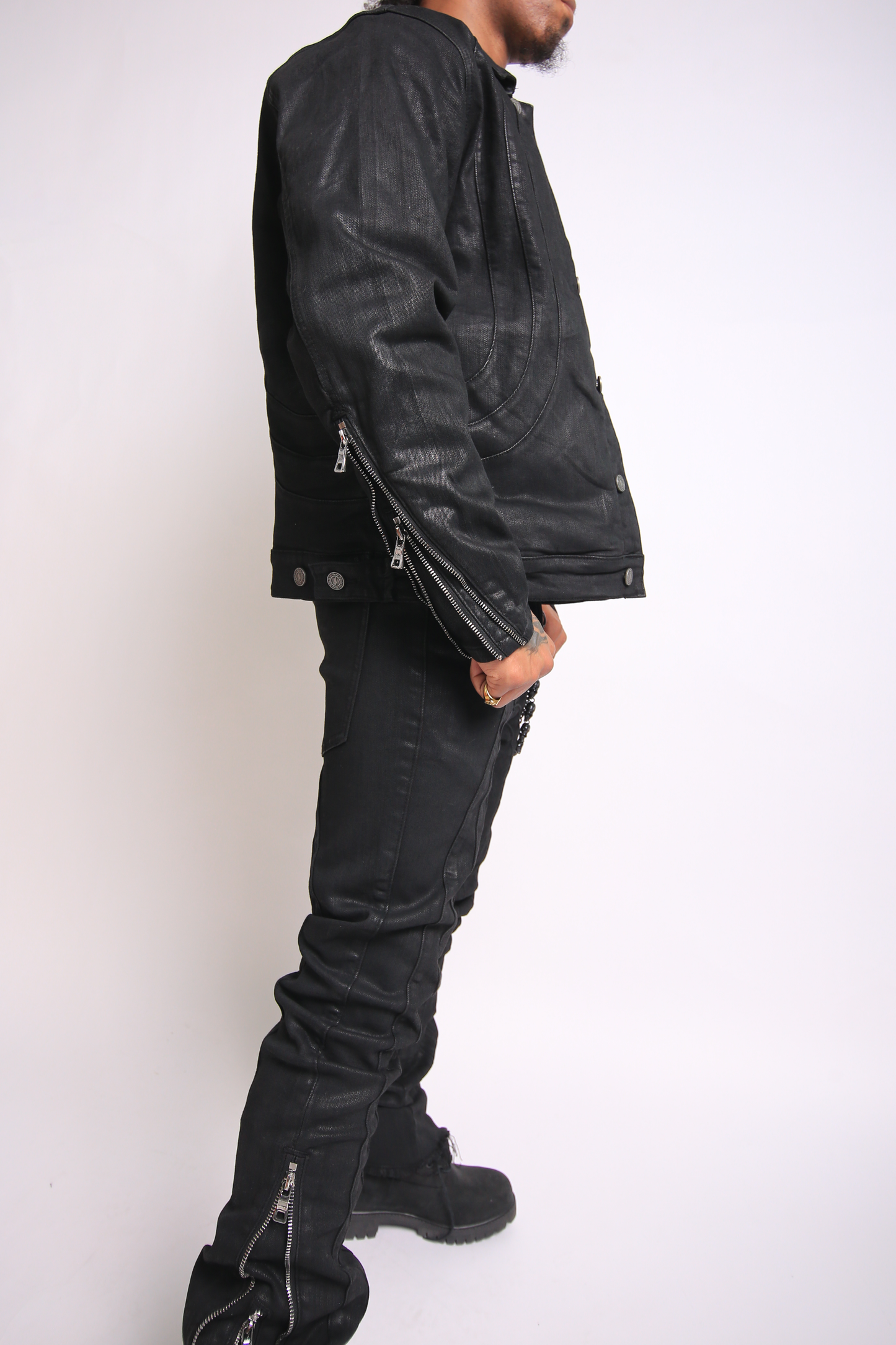 Person wearing a black leather jacket and pants on a white background