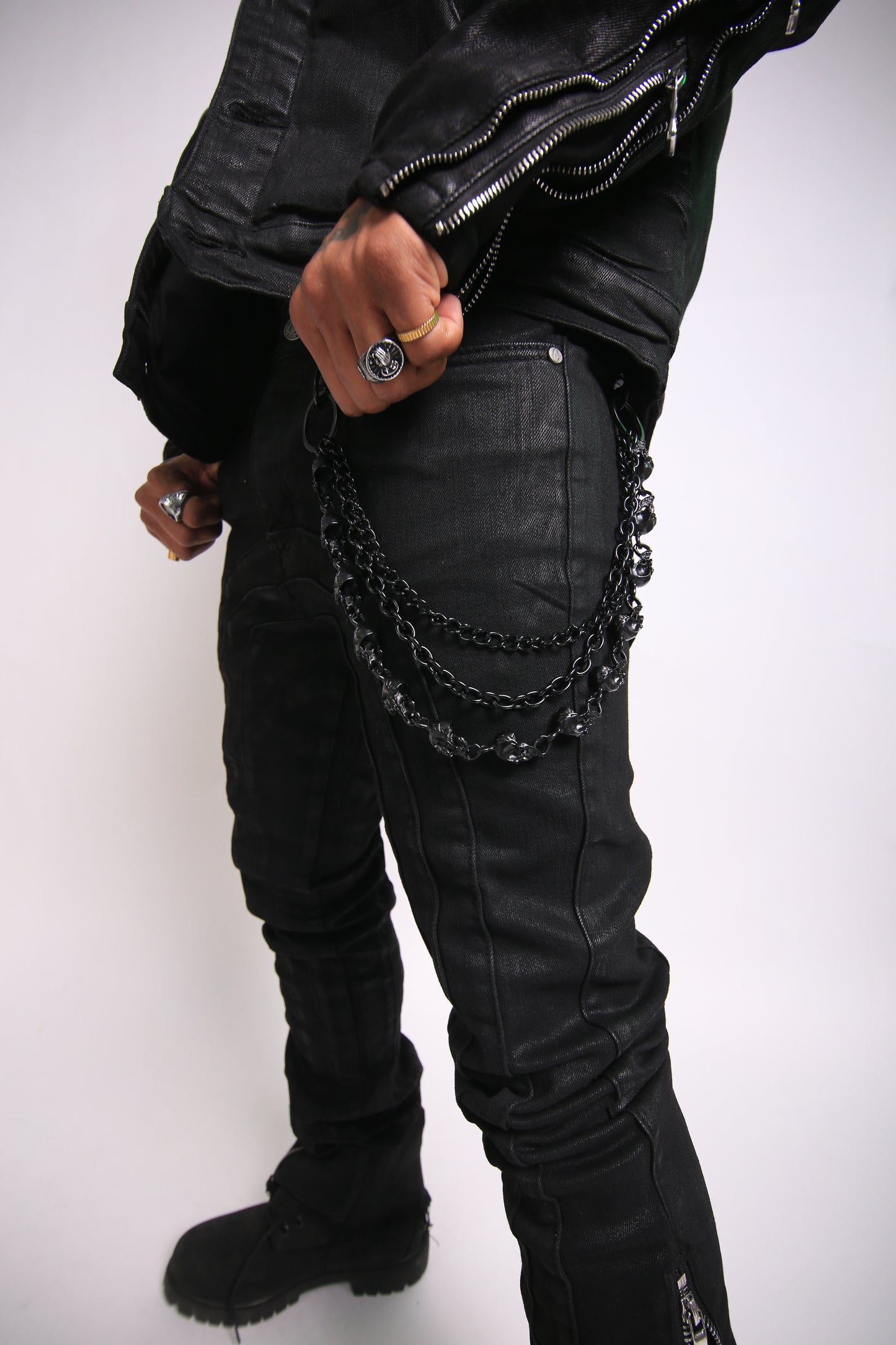 Person wearing a black leather jacket with chain details on a white background