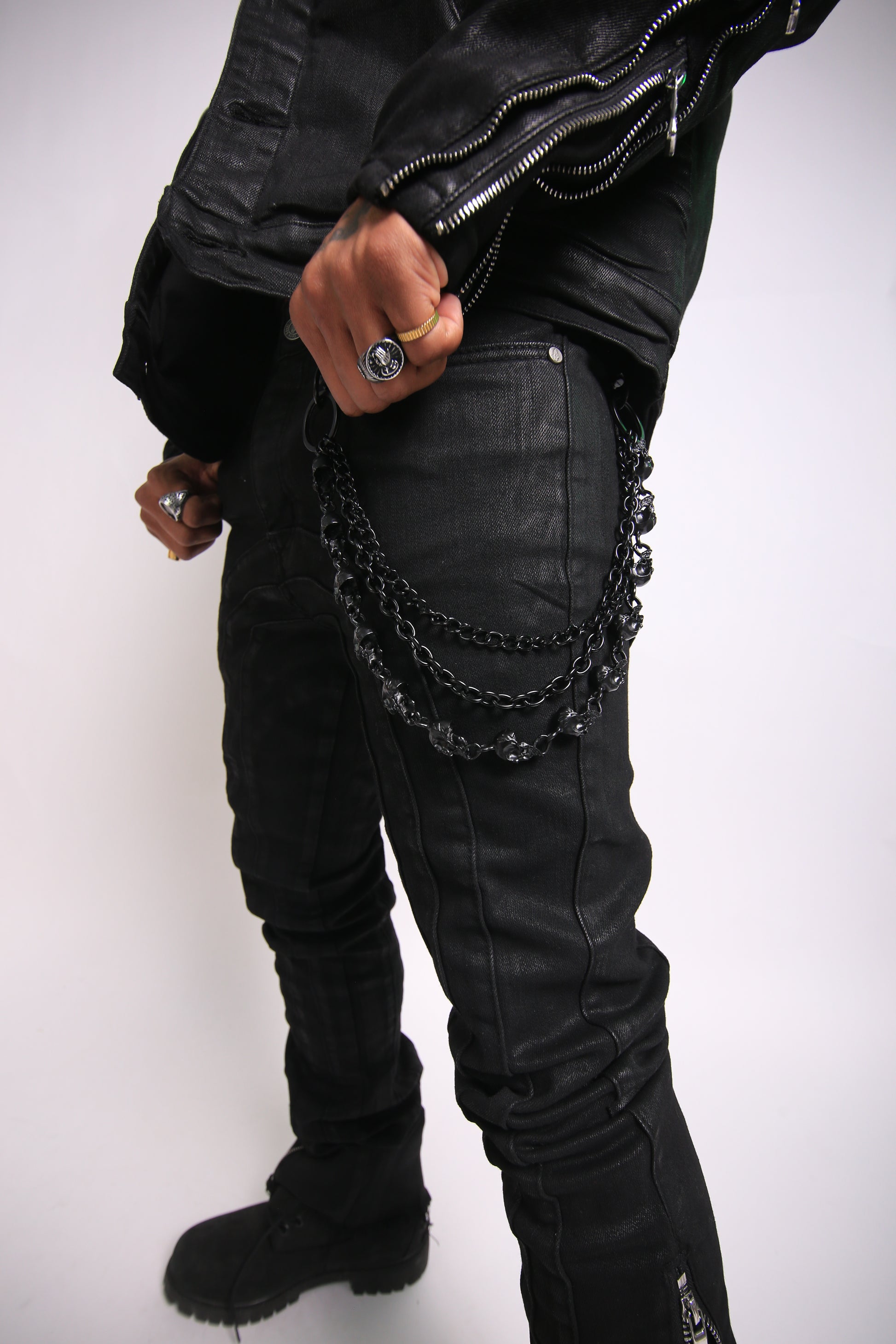 Person wearing a black leather jacket with chain details on a white background