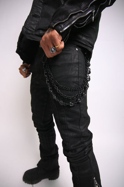 Person wearing a black leather jacket with chain details on a white background