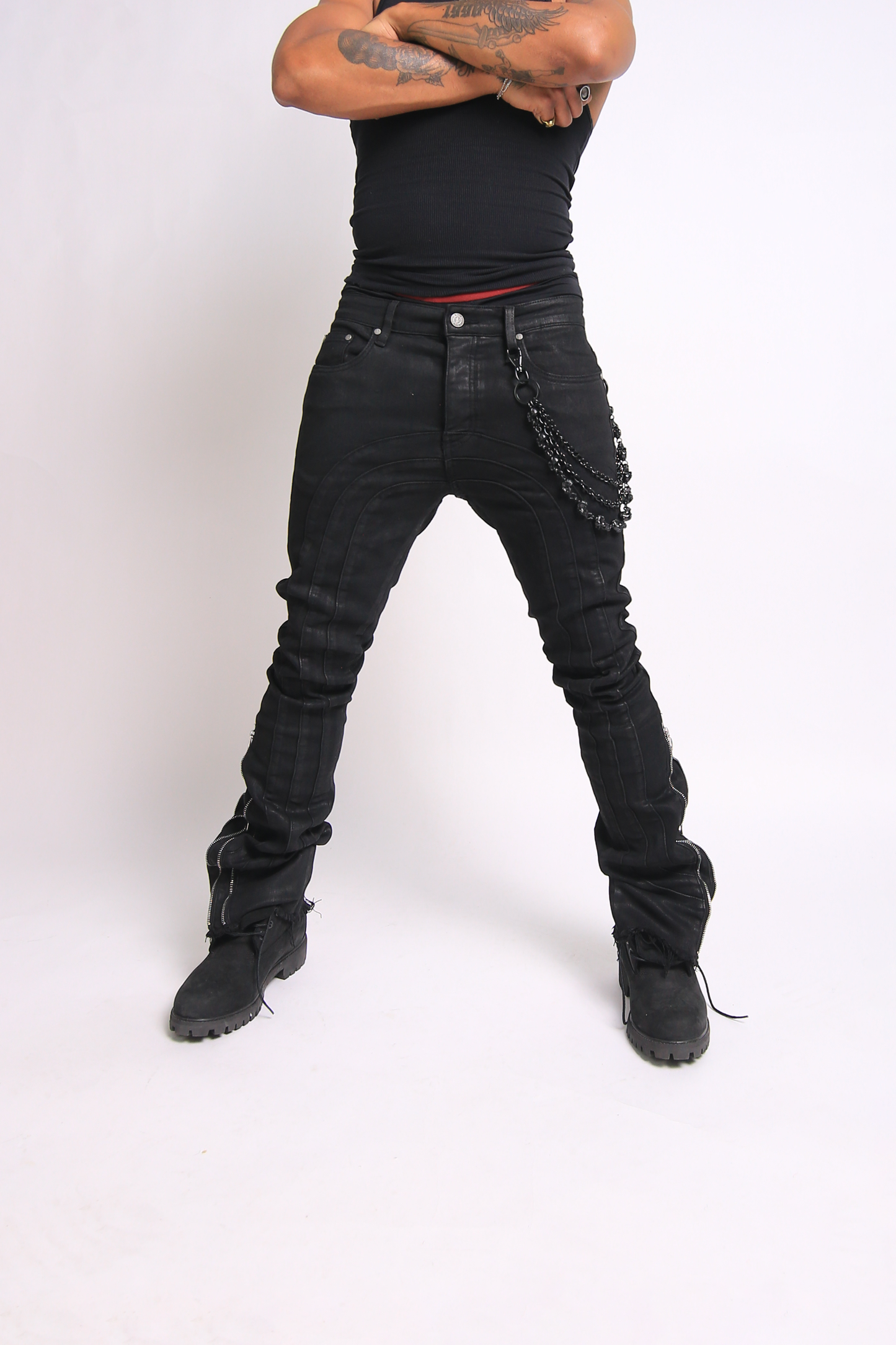 Person wearing black distressed jeans and black boots on a white background