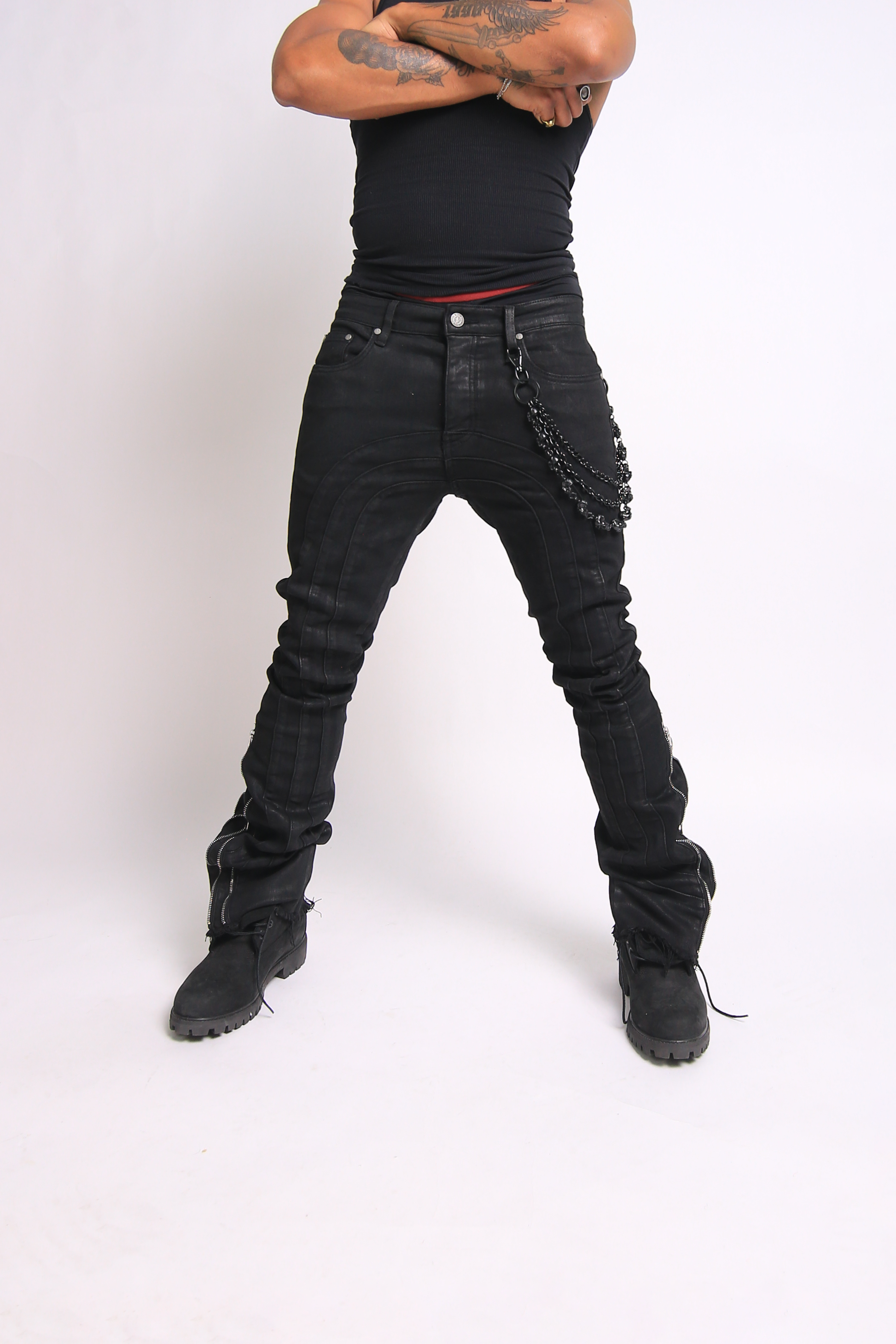 Person wearing black distressed jeans and black boots on a white background