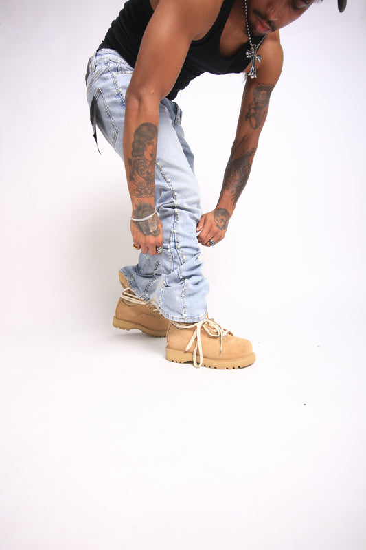 Person wearing tan boots and light blue jeans on a white background