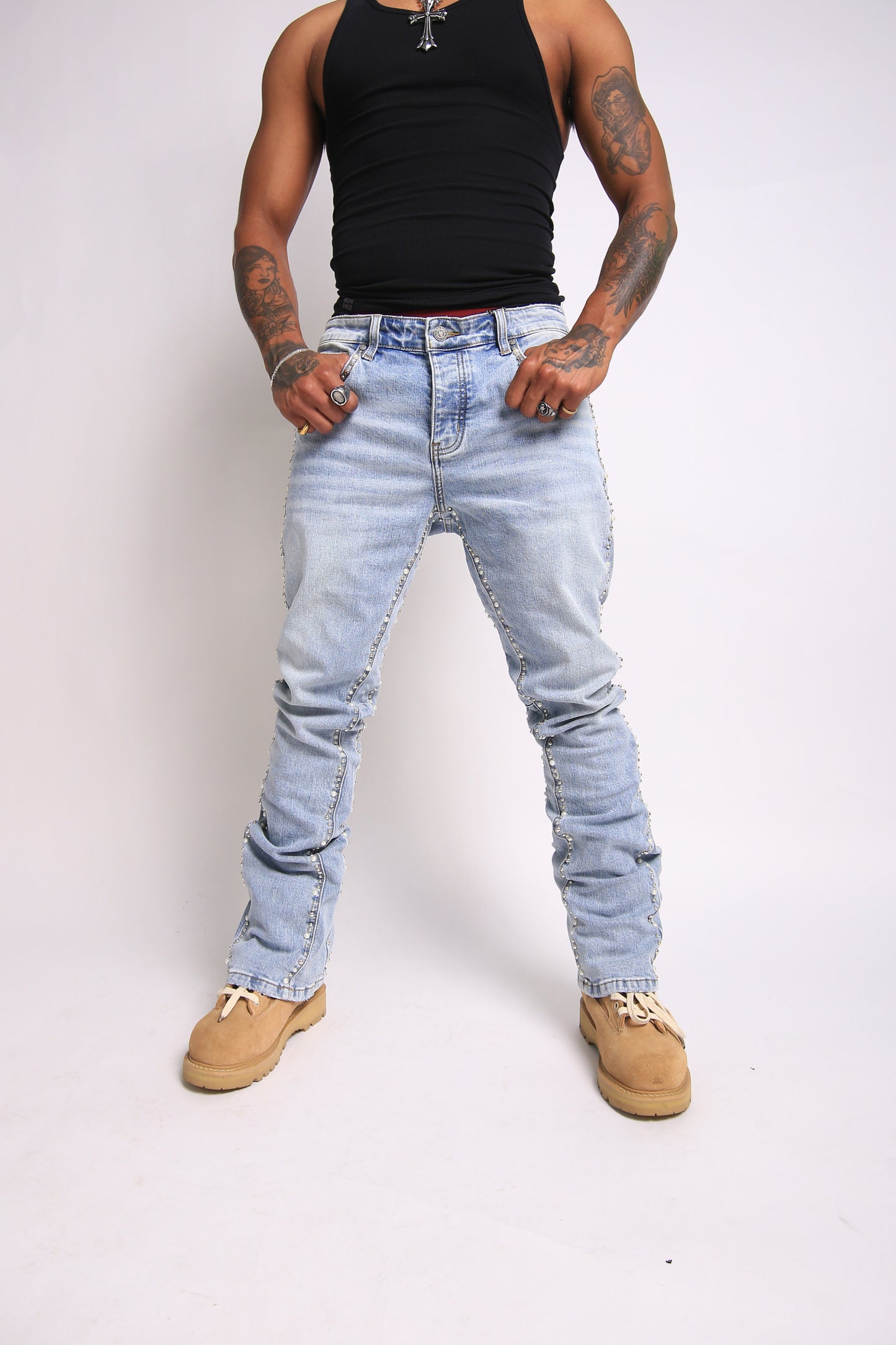 Person wearing light blue distressed jeans and a black tank top on a white background