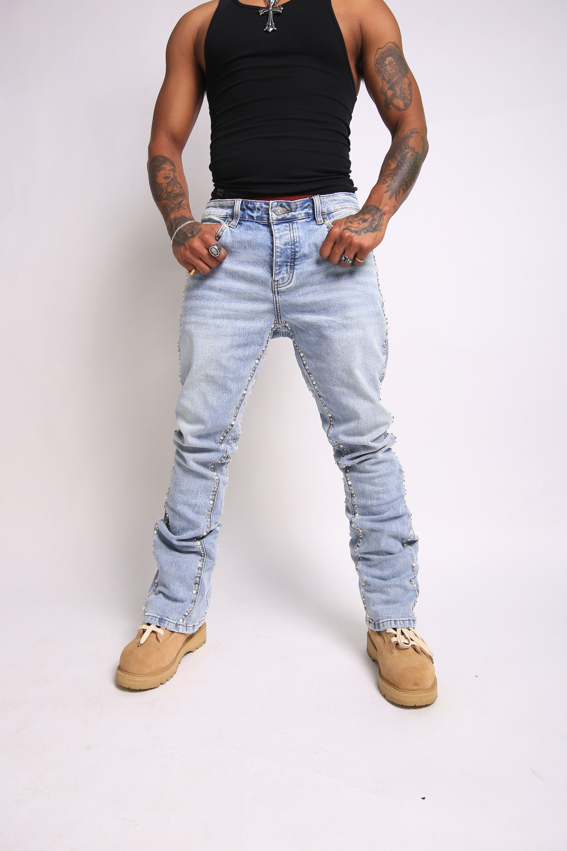 Person wearing light blue distressed jeans and a black tank top on a white background