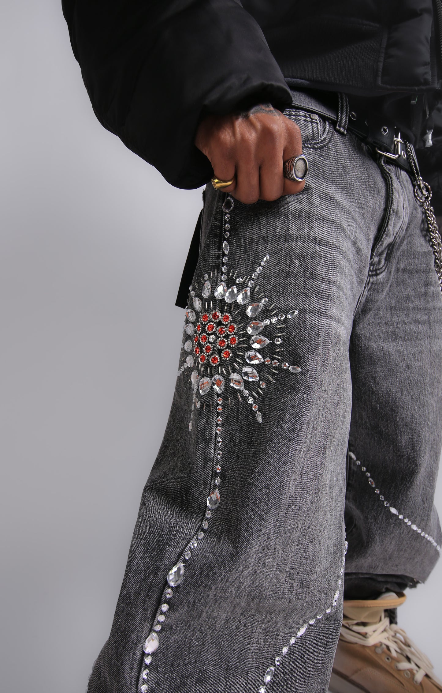 Gray jeans with decorative embellishments on a plain background
