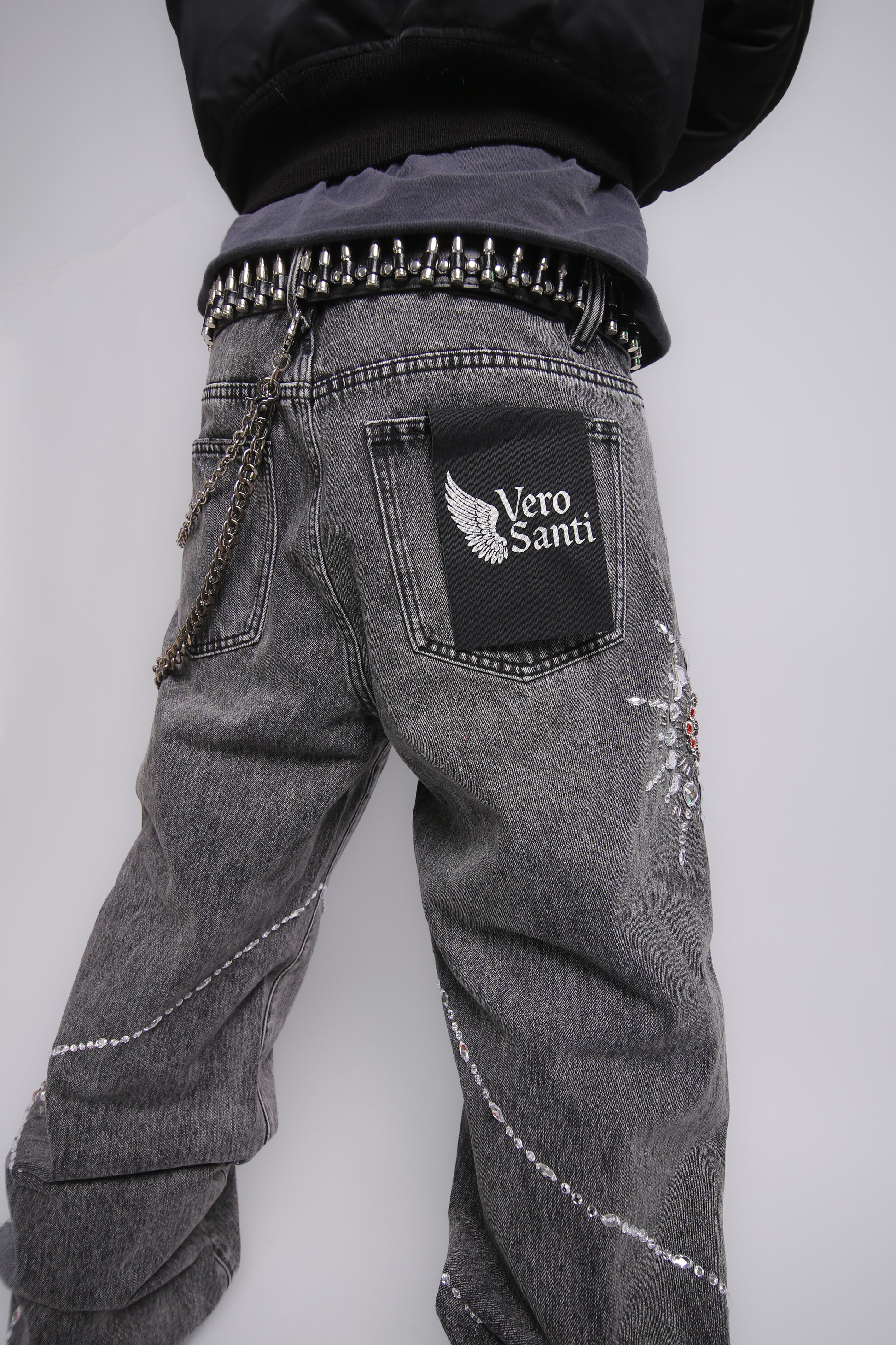 Gray jeans with decorative elements and a visible brand logo on a plain background