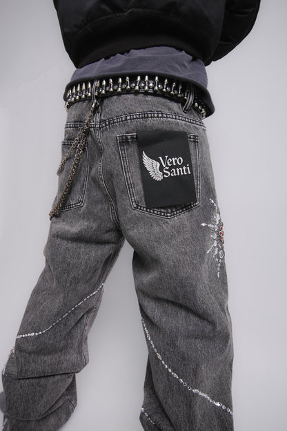 Gray jeans with decorative elements and a visible brand logo on a plain background