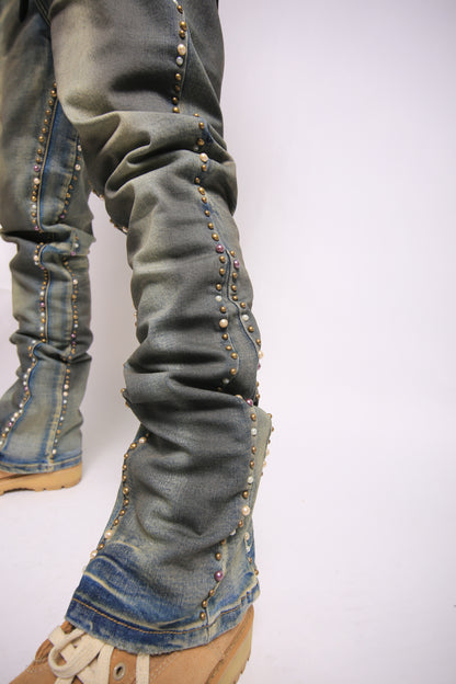 Close-up of blue jeans with decorative studs on a white background