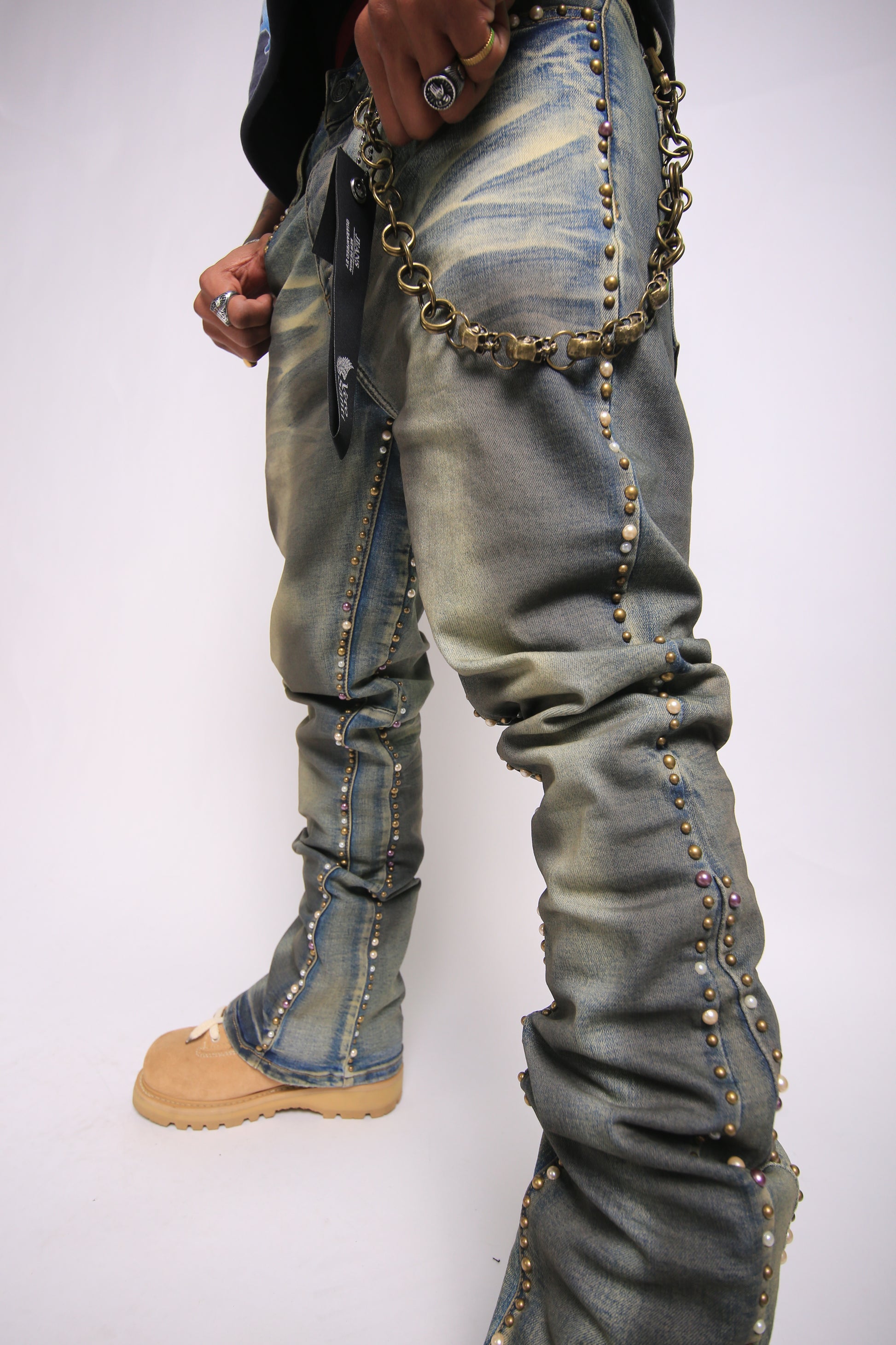 Person wearing embellished jeans with chains on a white background