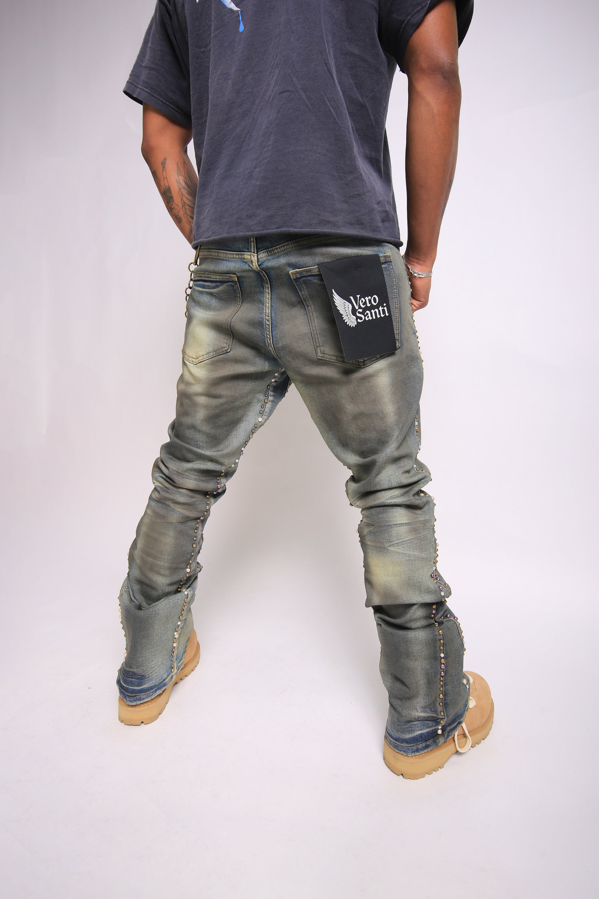 Person wearing distressed jeans with a visible brand logo on a plain background