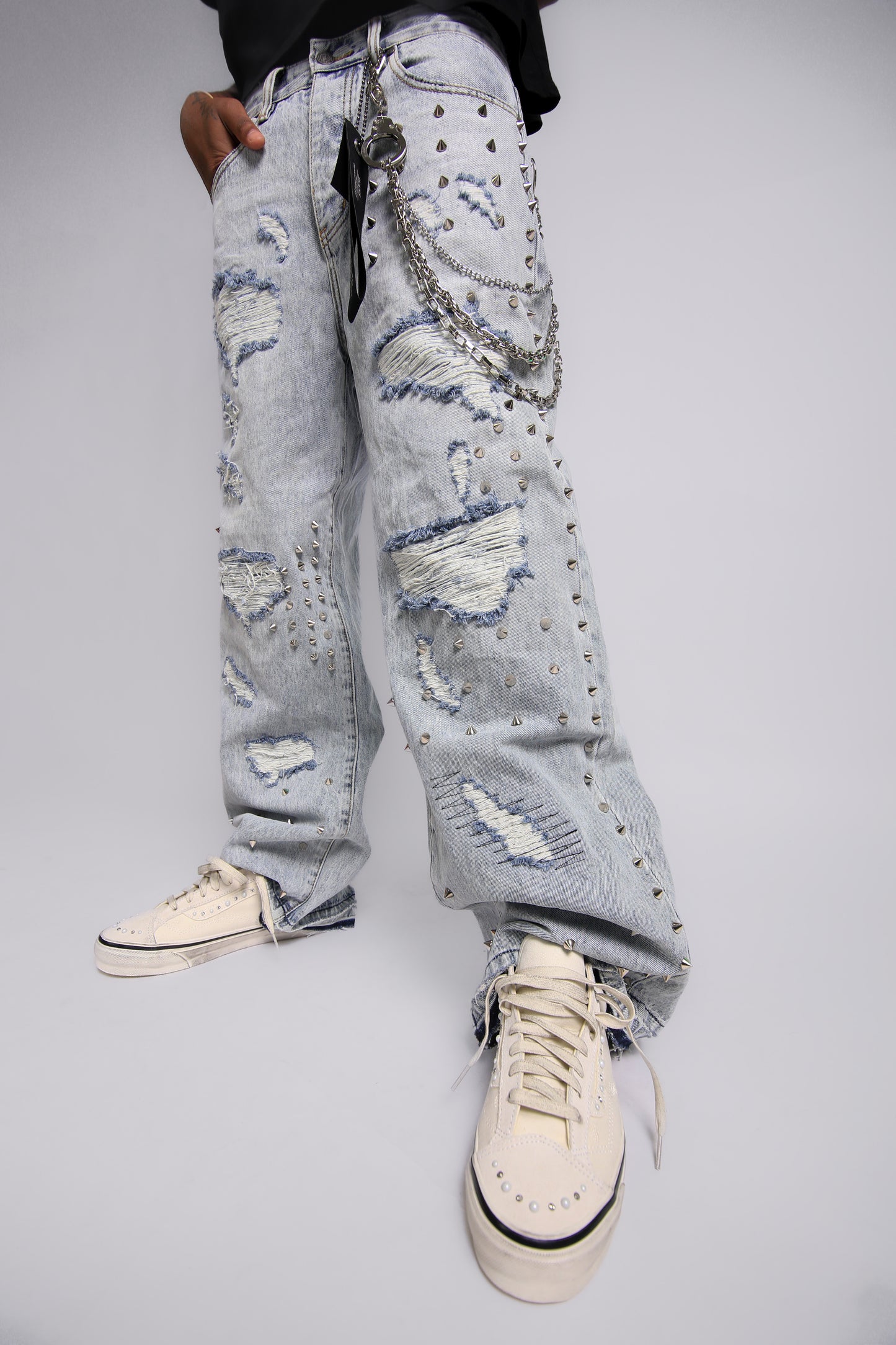 Distressed light blue jeans worn by a person on a plain background