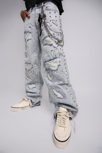 Distressed light blue jeans worn by a person on a plain background