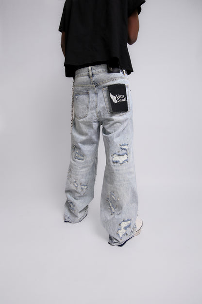 Person wearing light gray distressed jeans with a Vero Santi black patch on a white background