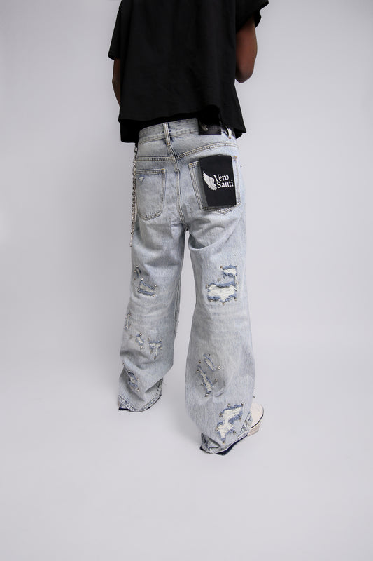 Person wearing light gray distressed jeans with a Vero Santi black patch on a white background