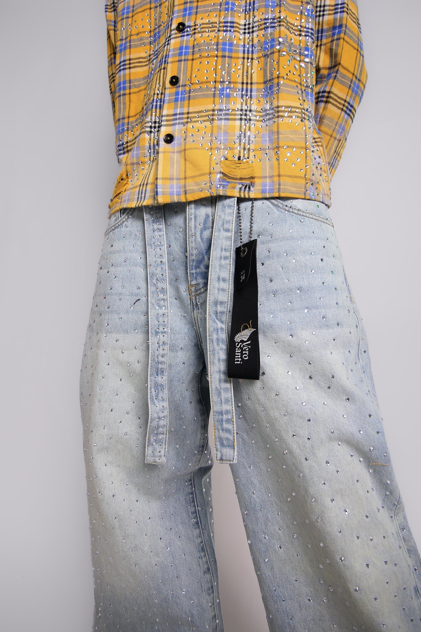 Person wearing a yellow plaid shirt and light blue jeans with a brand tag on a gray background