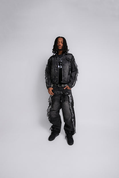 Person wearing a black denim jacket and pants on a white background