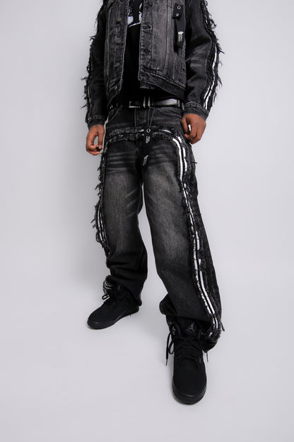 Person wearing a black distressed jacket, jeans, and boots on a white background