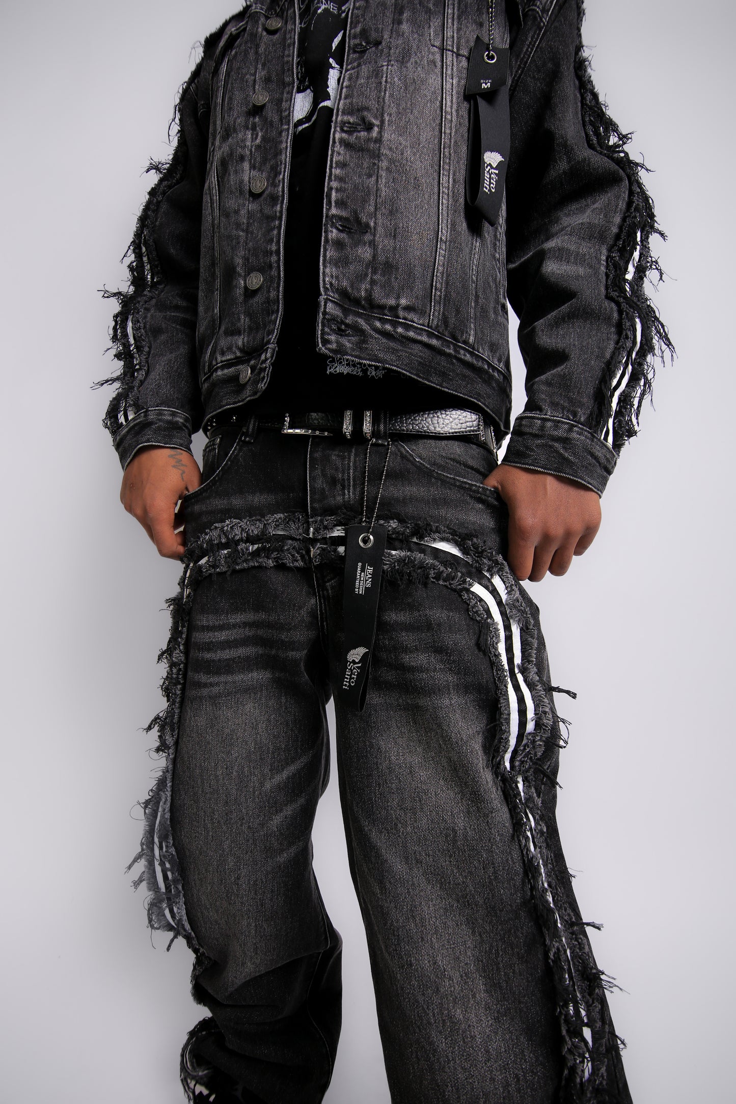Person wearing a black distressed jacket and jeans on a white background
