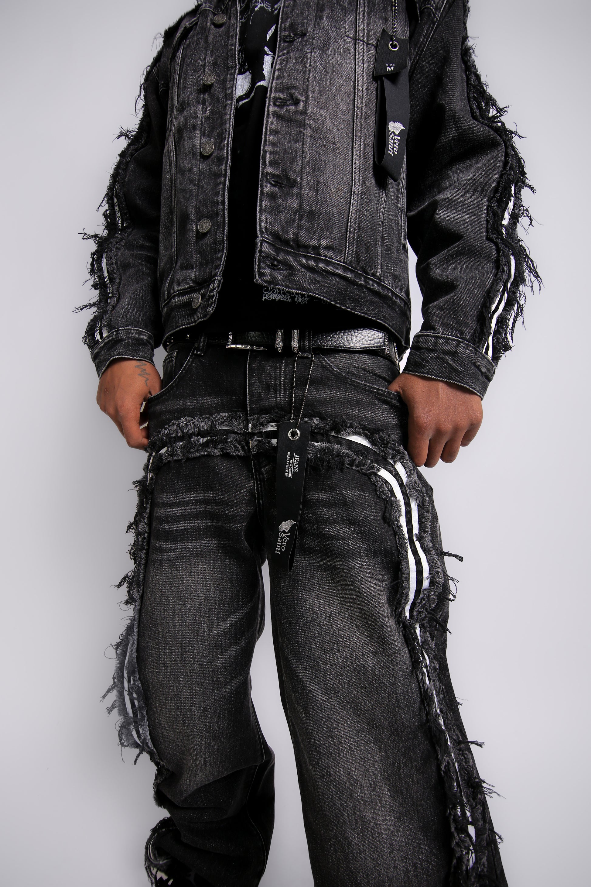 Person wearing a black distressed jacket and jeans on a white background