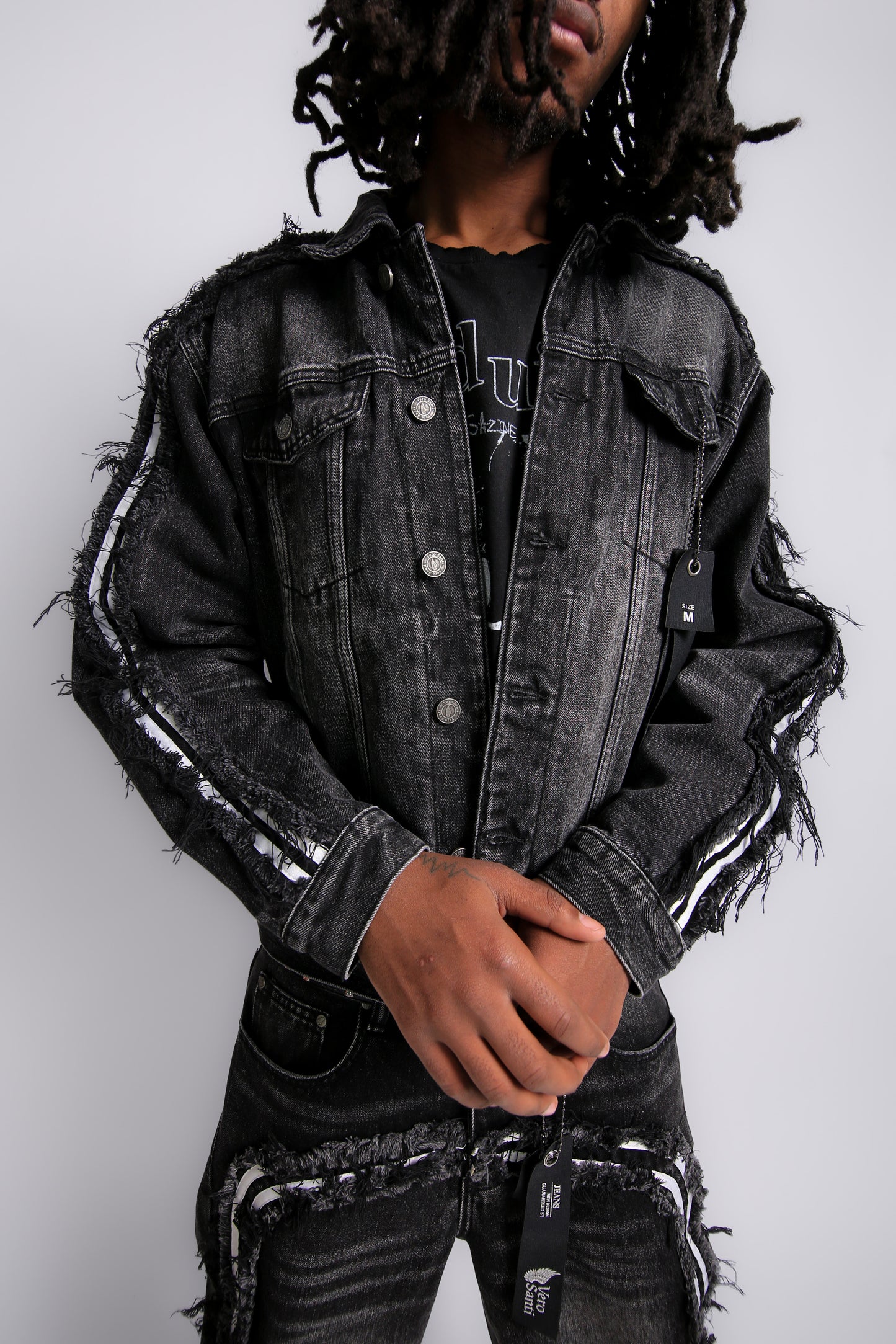 Person wearing a black distressed denim jacket on a white background