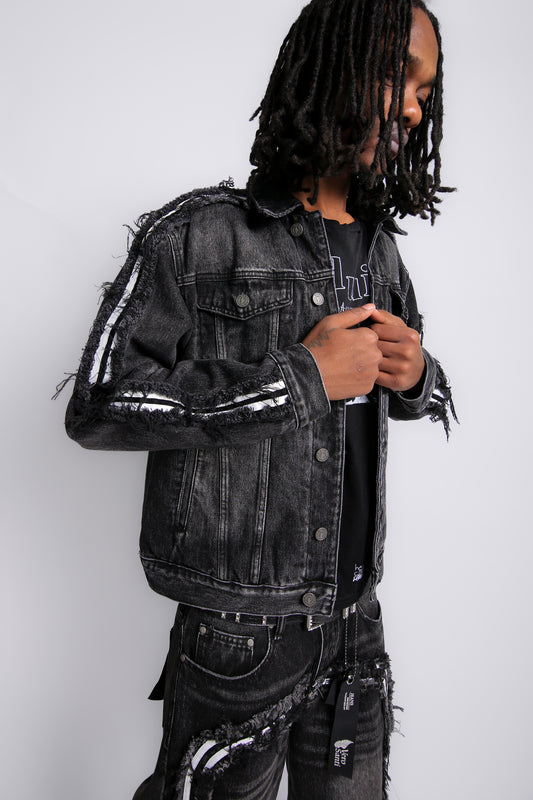 Person wearing a black distressed denim jacket against a white background