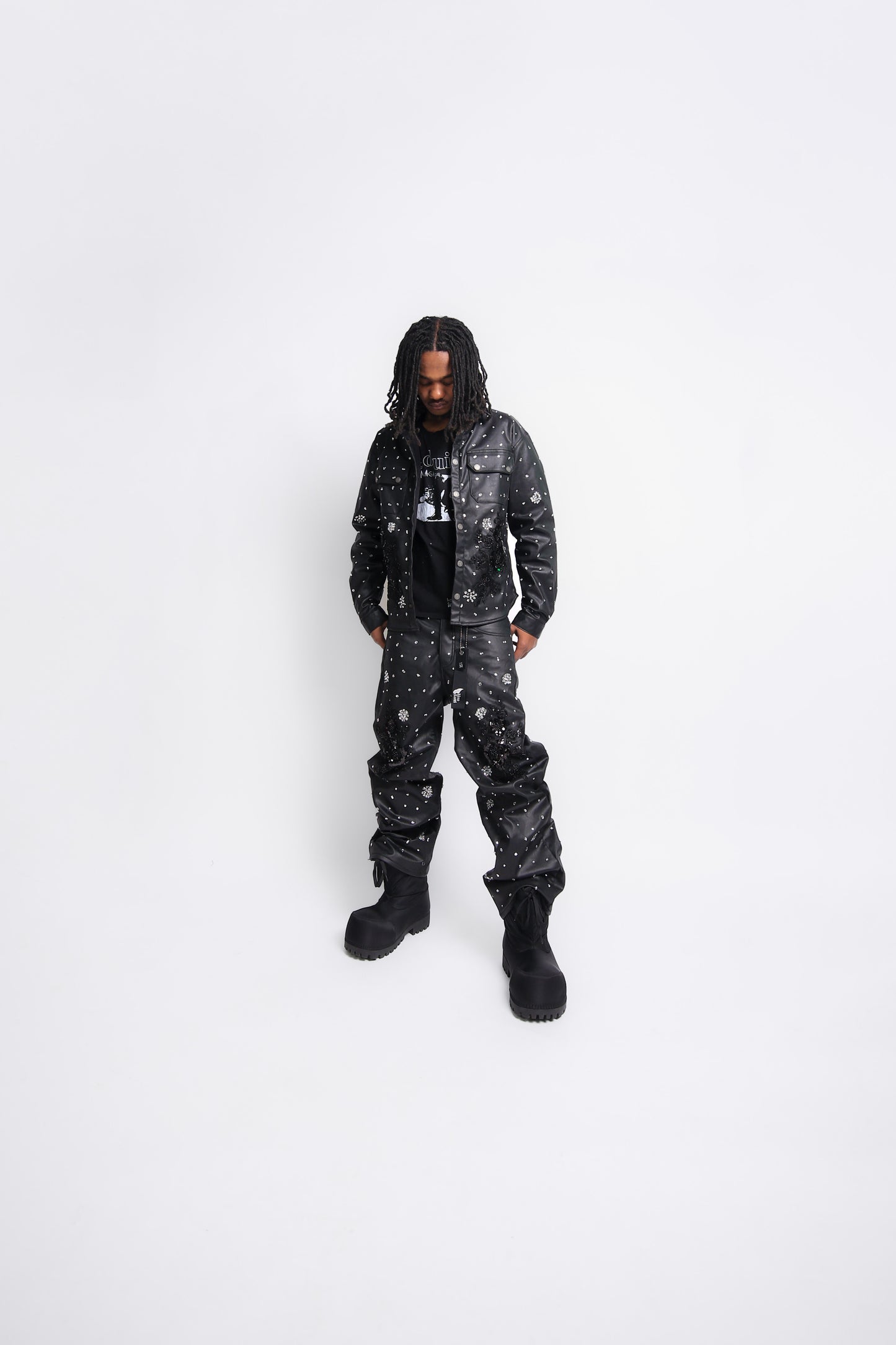 Person wearing a black leather jacket and leather pants on a white background