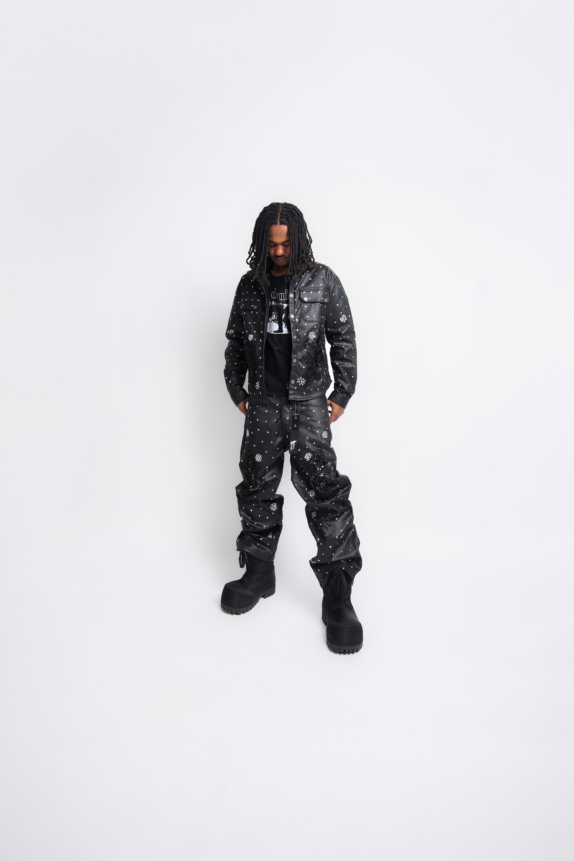 Person wearing a black leather jacket and leather pants on a white background