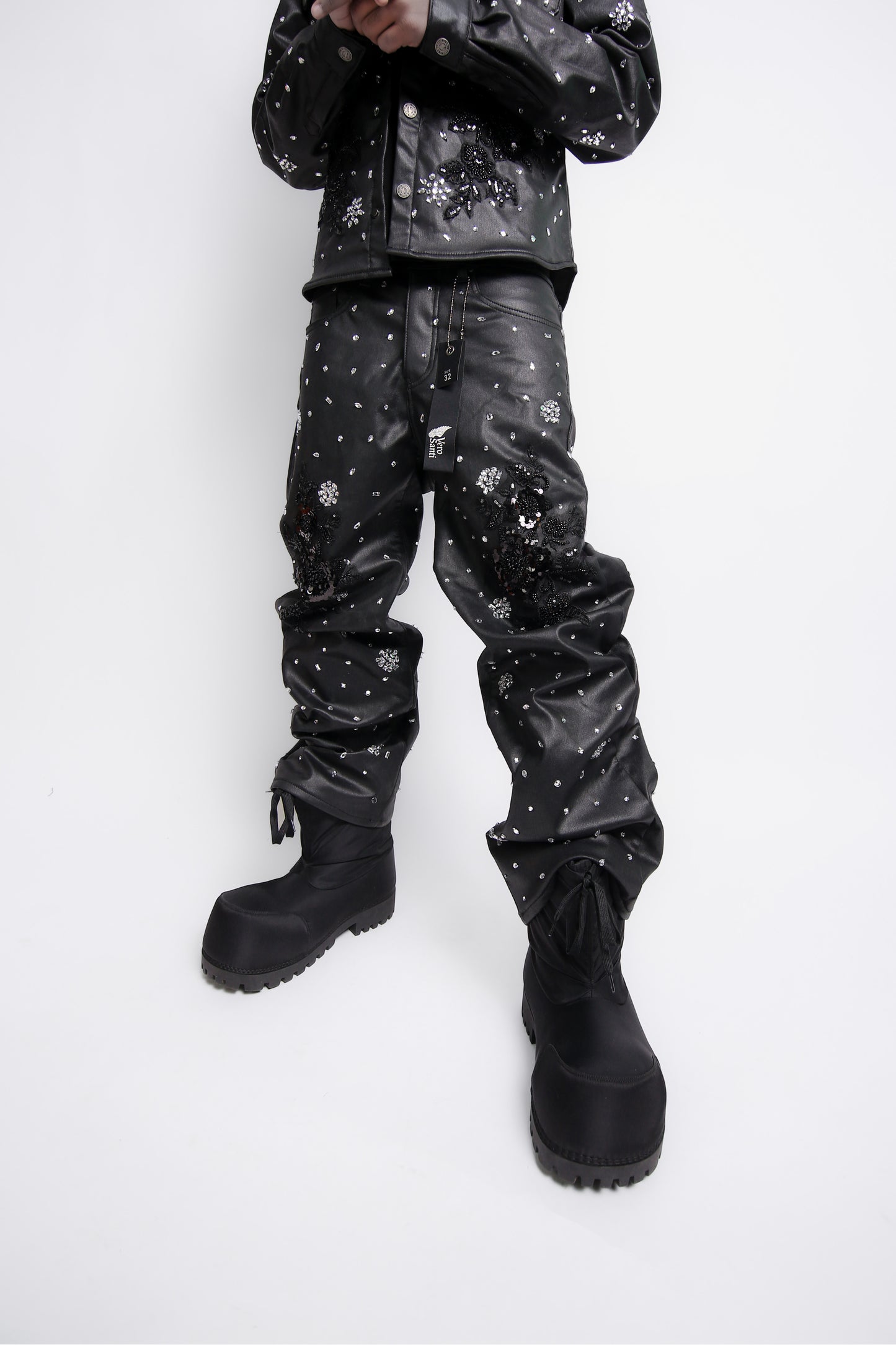 Person wearing black leather pants with white patterns on a white background