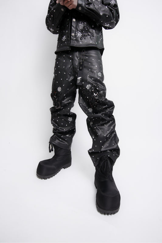 Person wearing black leather pants with white patterns on a white background