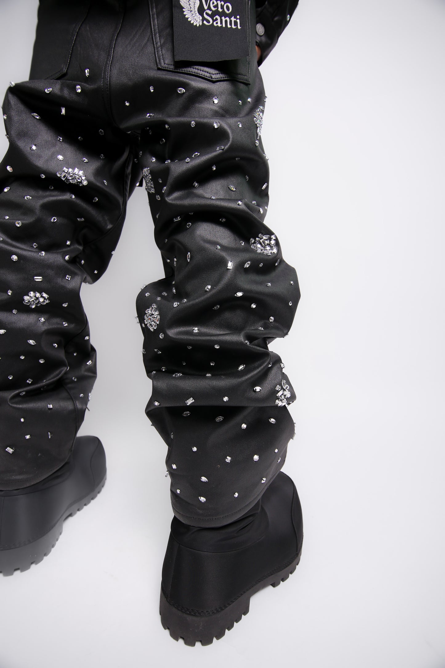 Black leather pants with white embellishments and black boots on a white background