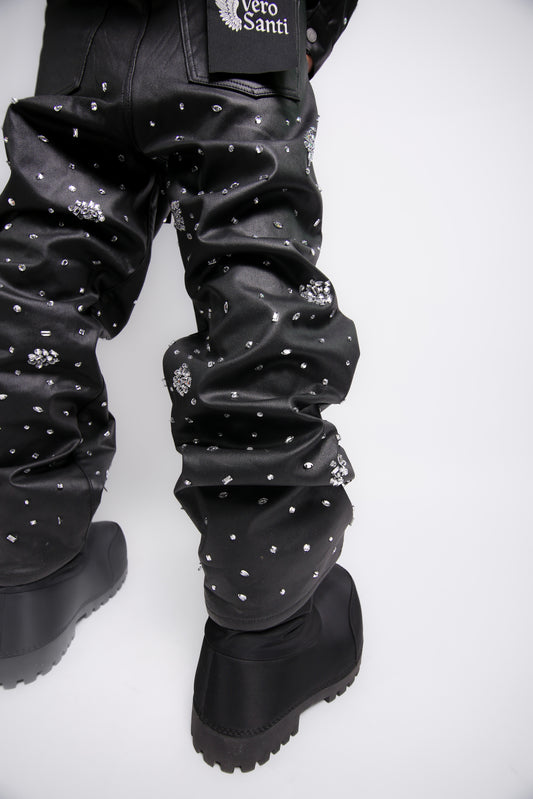 Black leather pants with white embellishments and black boots on a white background