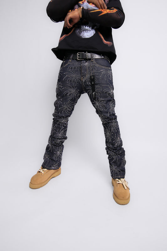 Person wearing black patterned jeans and a black hoodie on a white background