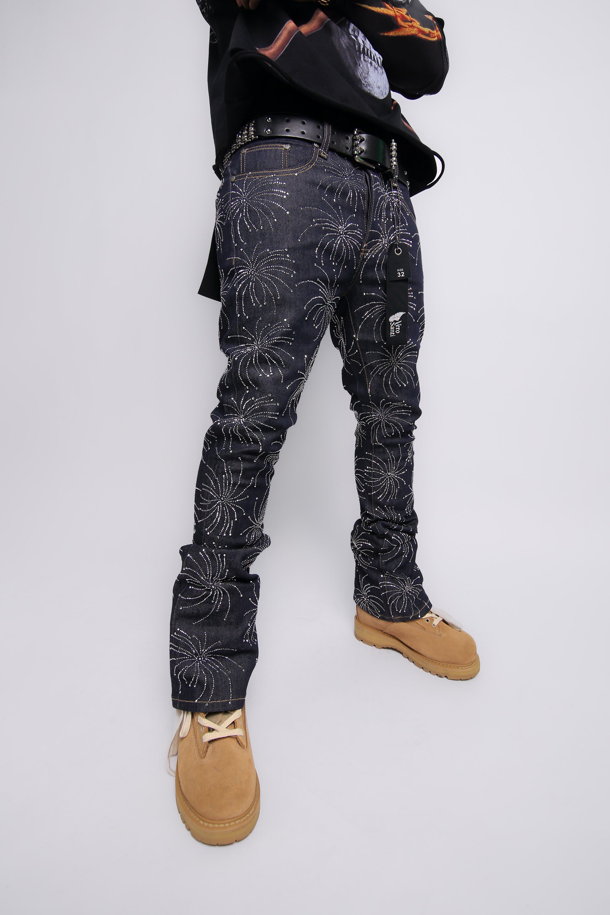 Person wearing dark jeans with a floral pattern and tan shoes on a white background