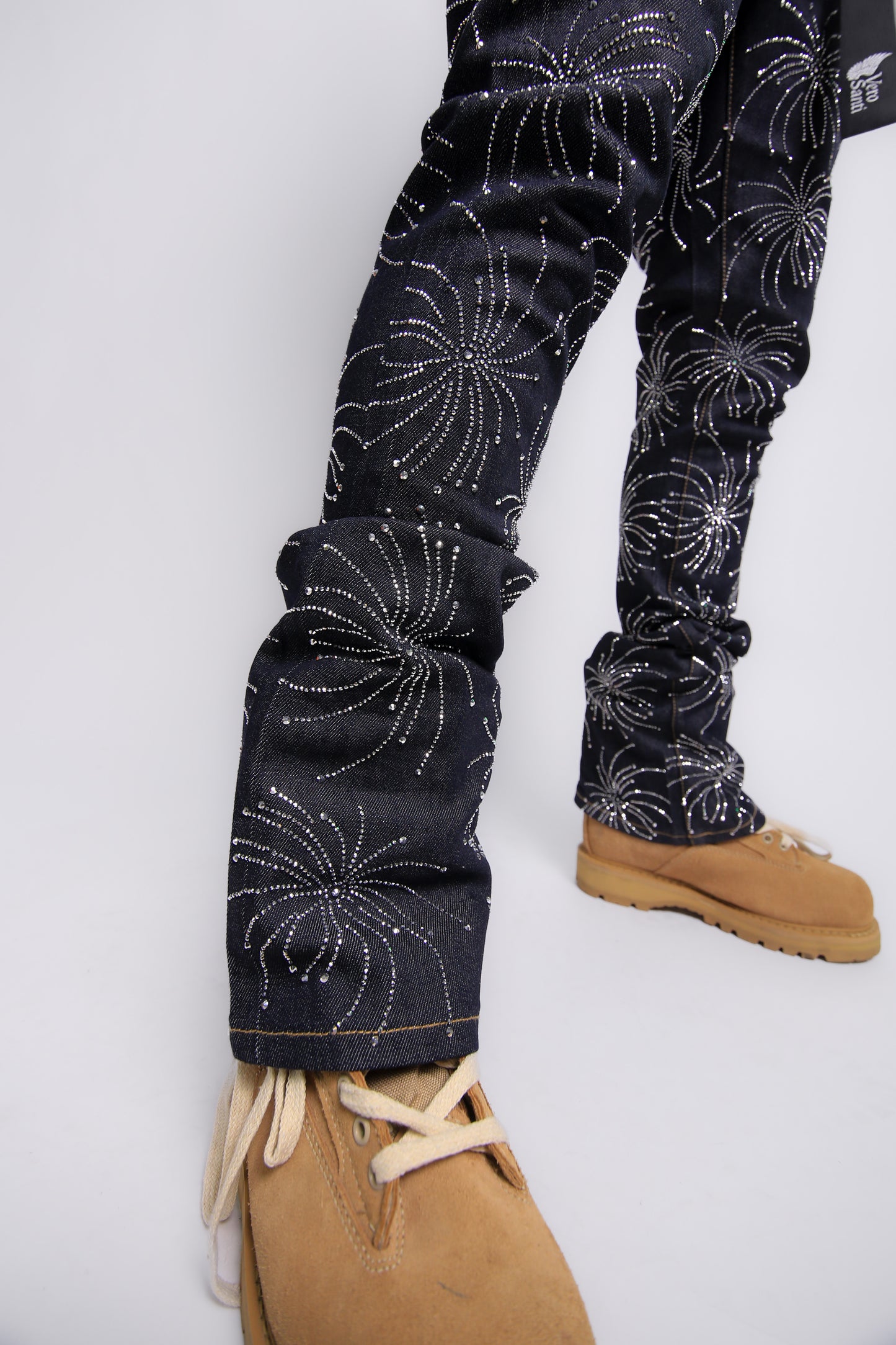 Black pants with white floral patterns worn by a person on a white background