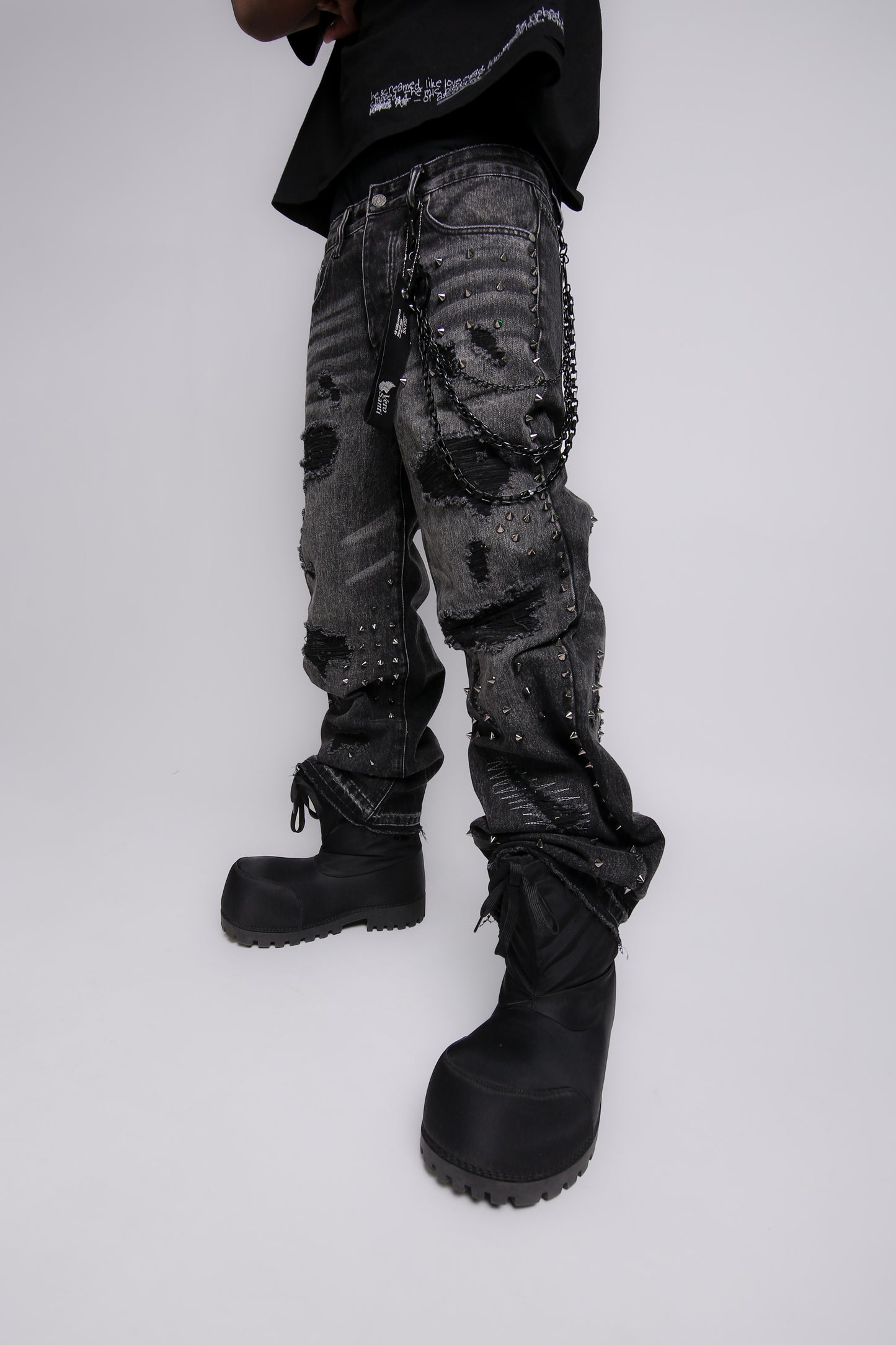 Person wearing dark camouflage pants and black boots on a white background