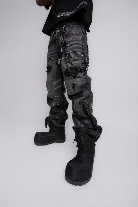 Person wearing dark camouflage pants and black boots on a white background