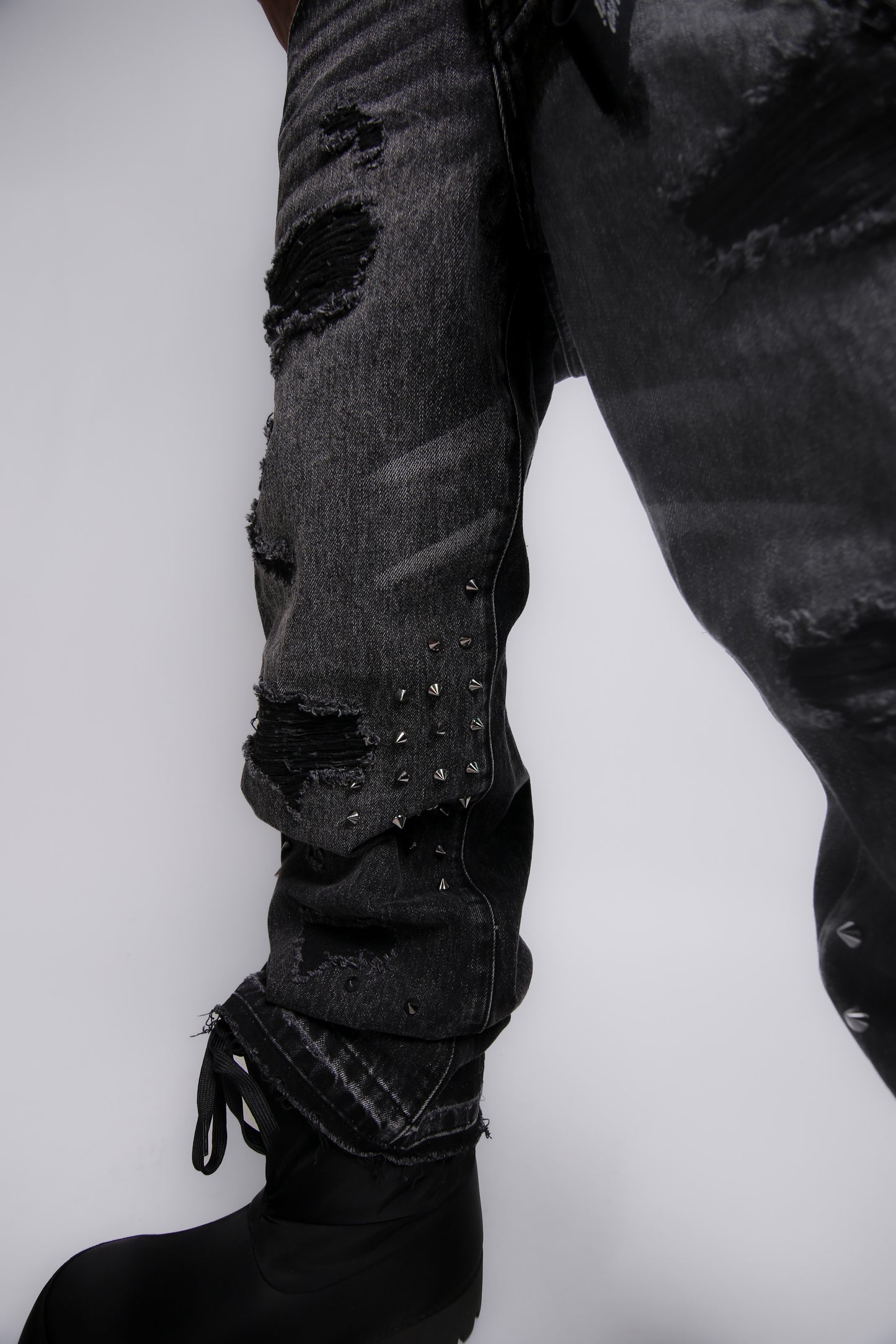 Ripped black jeans with studs on a white background