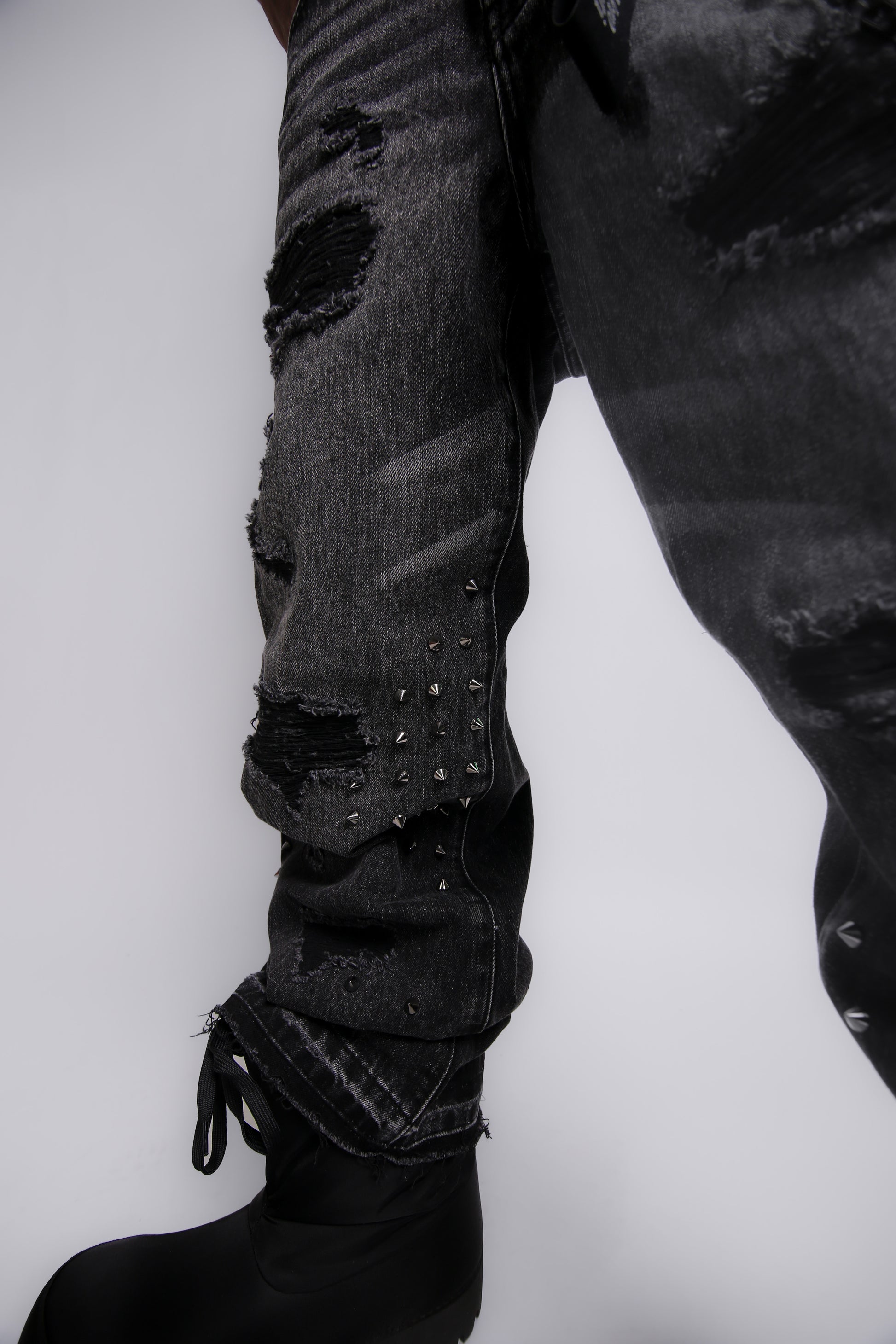Ripped black jeans with studs on a white background