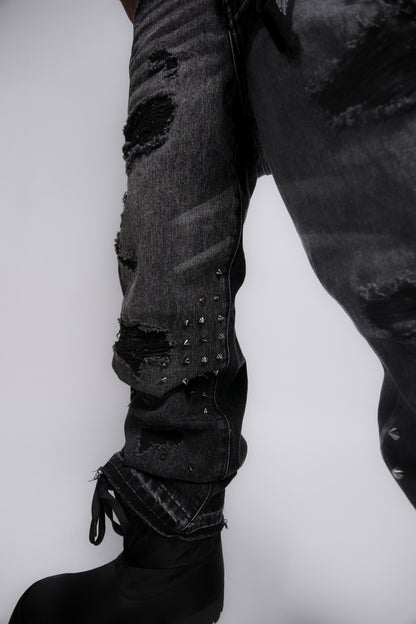 Ripped black jeans with studs on a white background