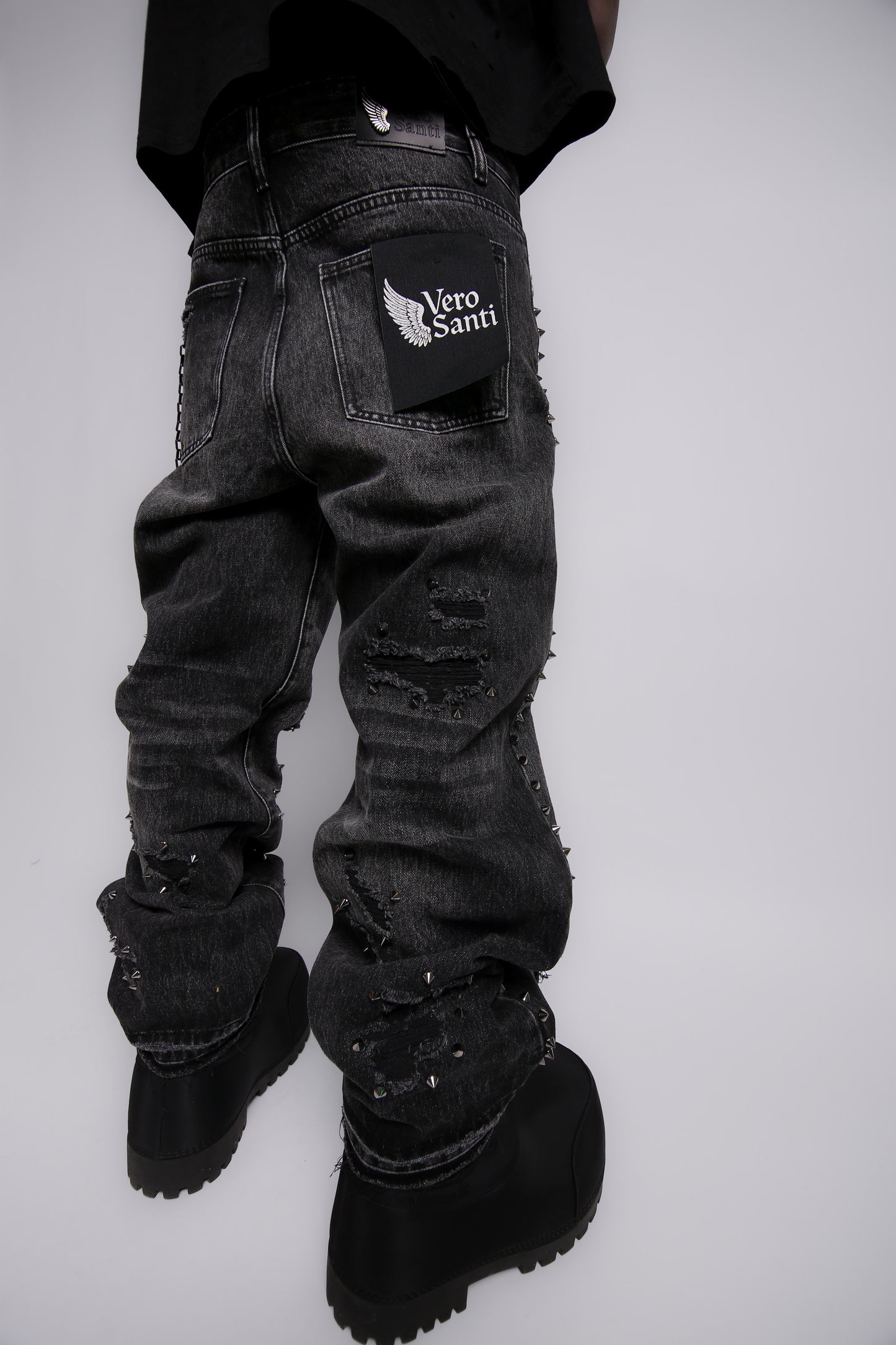 Black distressed jeans with a brand logo on a white background