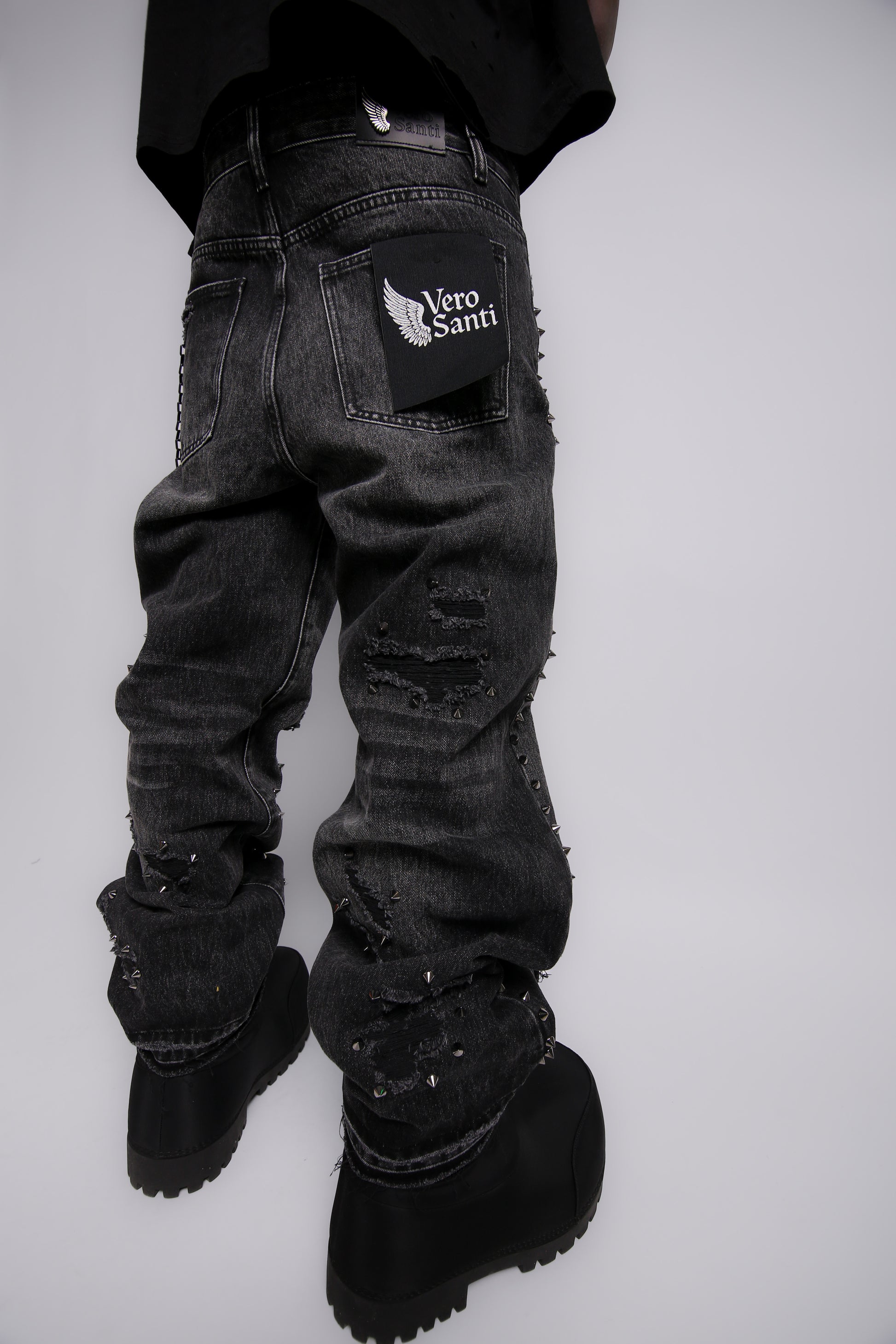 Black distressed jeans with a brand logo on a white background